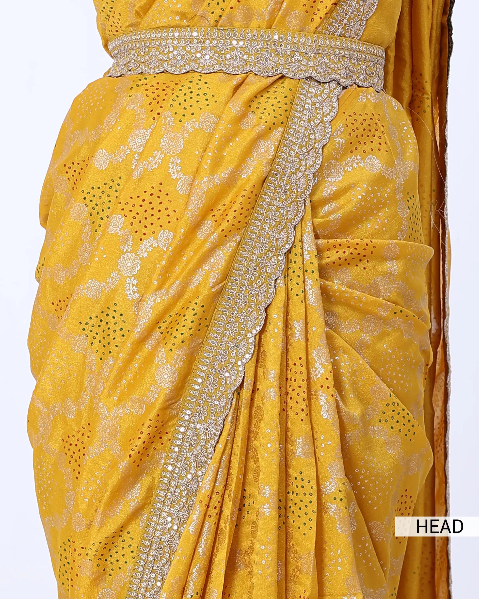 A close-up of a yellow saree with silver floral embroidery and a wide embellished border