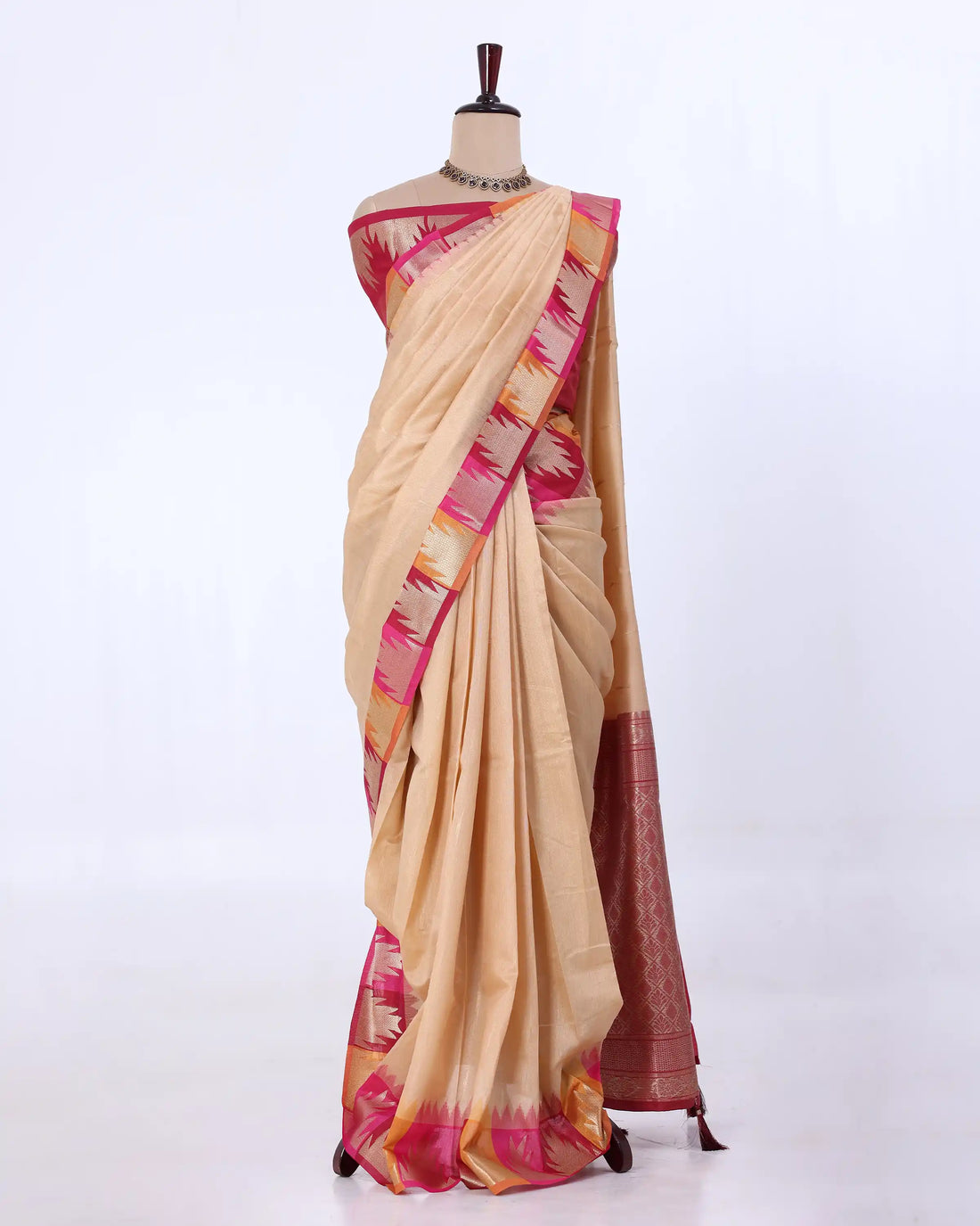 A pink silk saree with a metallic gold and beige geometric border
