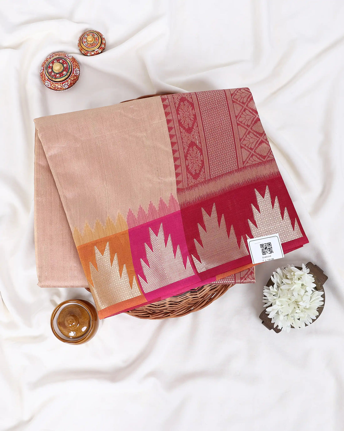 A beige cotton saree with a vibrant pink and orange ikat border and a dark brown zari-embellished pallu
