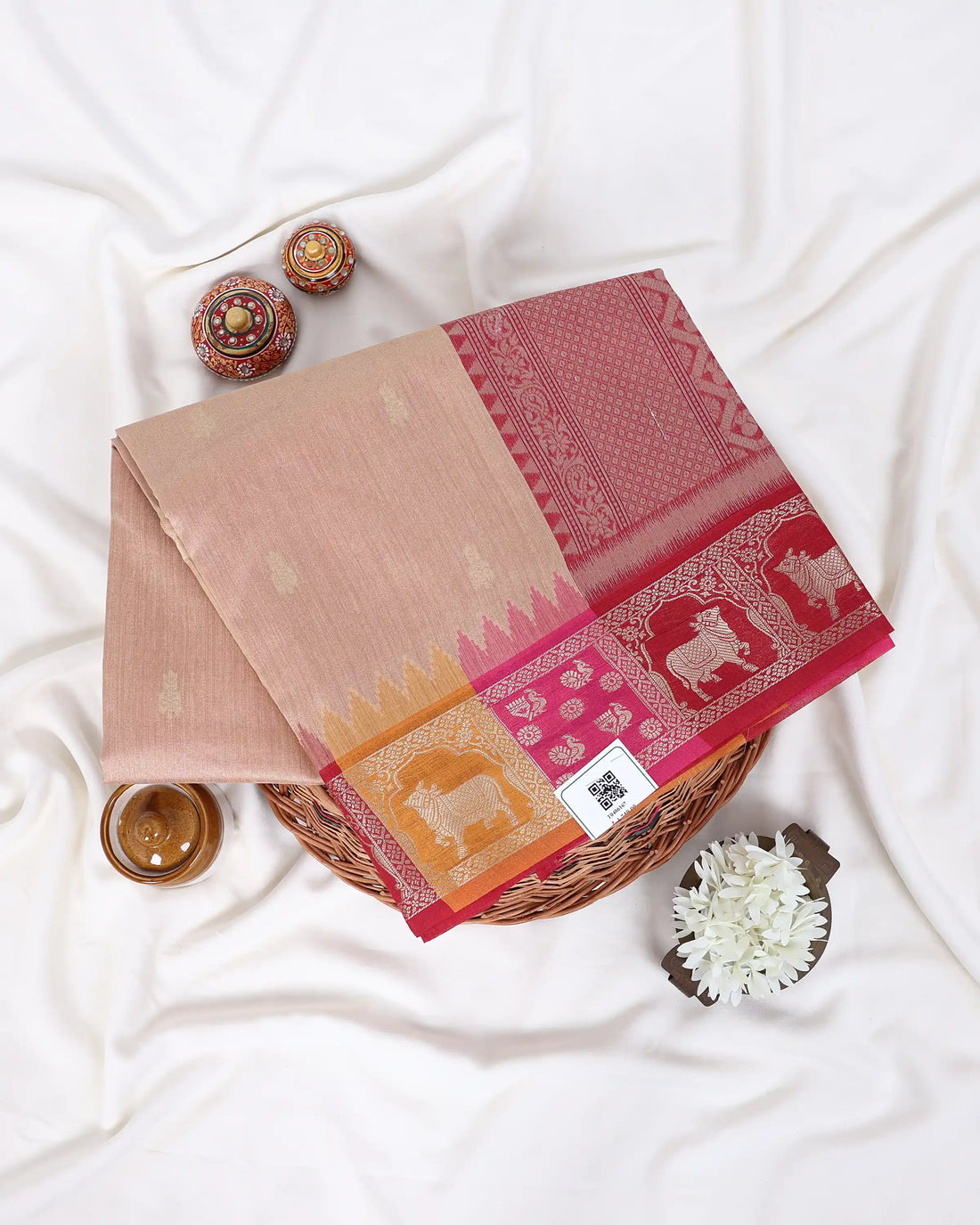 A beige raw silk saree with vibrant pink and yellow borders