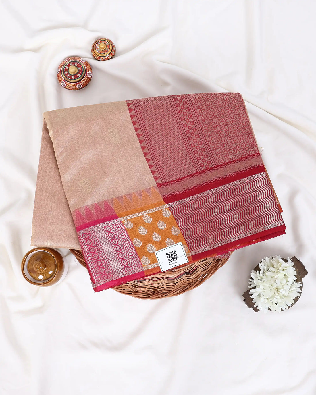 A beige raw silk saree with a pink and orange patterned border