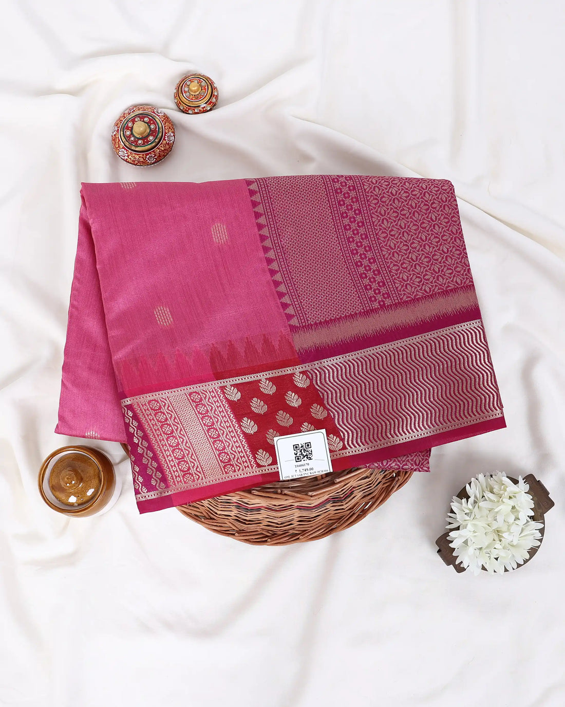 A pink raw silk saree with a wide metallic gold and silver border