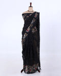 A black saree with floral and geometric patterns in red, beige, and white
