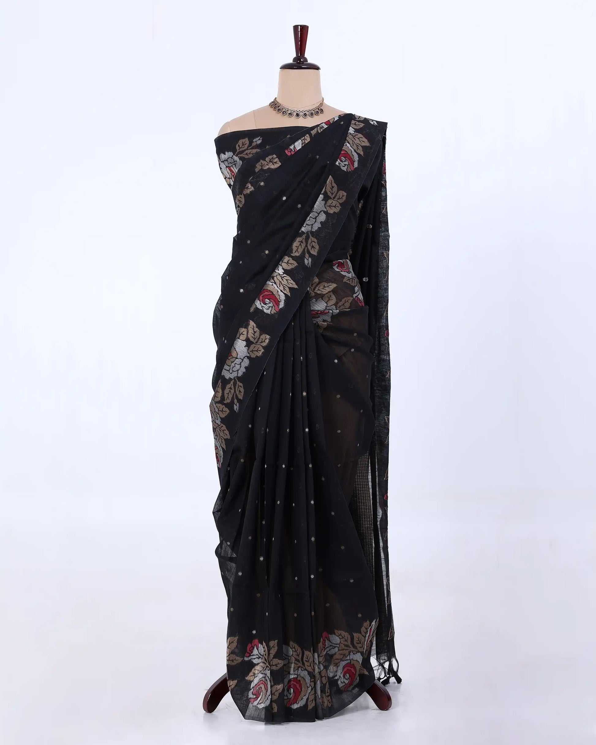 A black saree with floral and geometric patterns in red, beige, and white