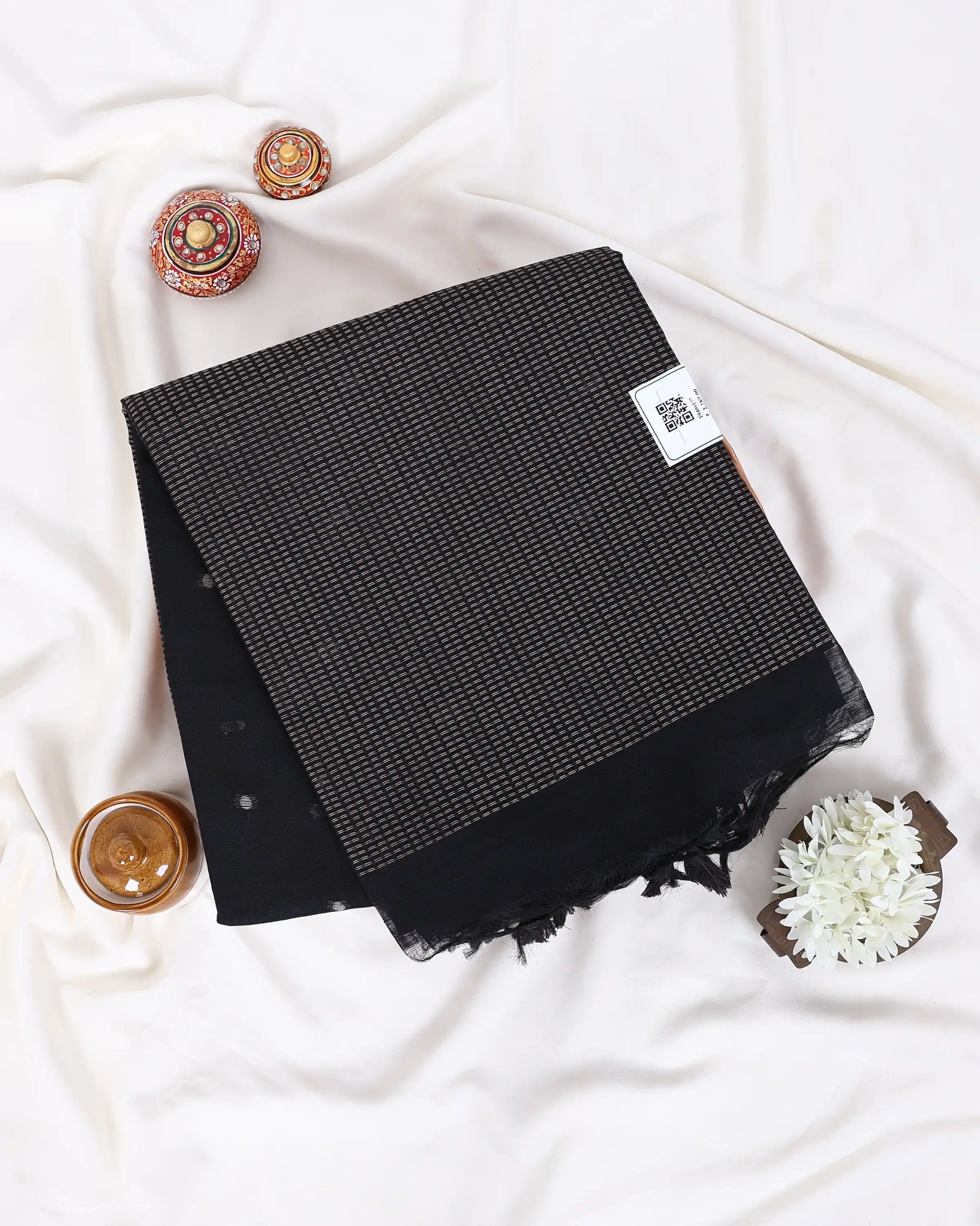 A folded black scarf with a subtle woven texture and fringed edges