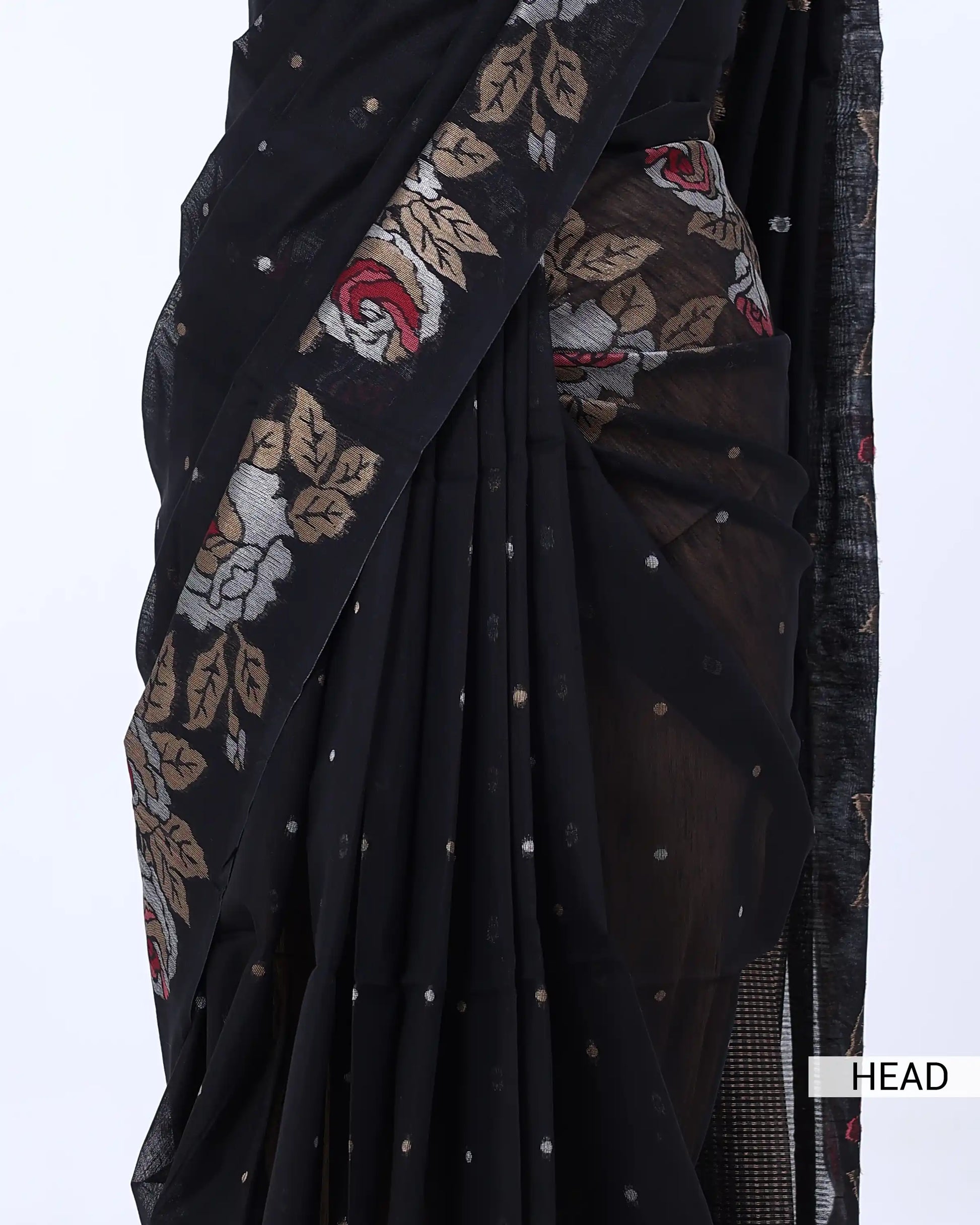 A close-up of a black saree with a sheer border featuring beige, red, and white floral embroidery