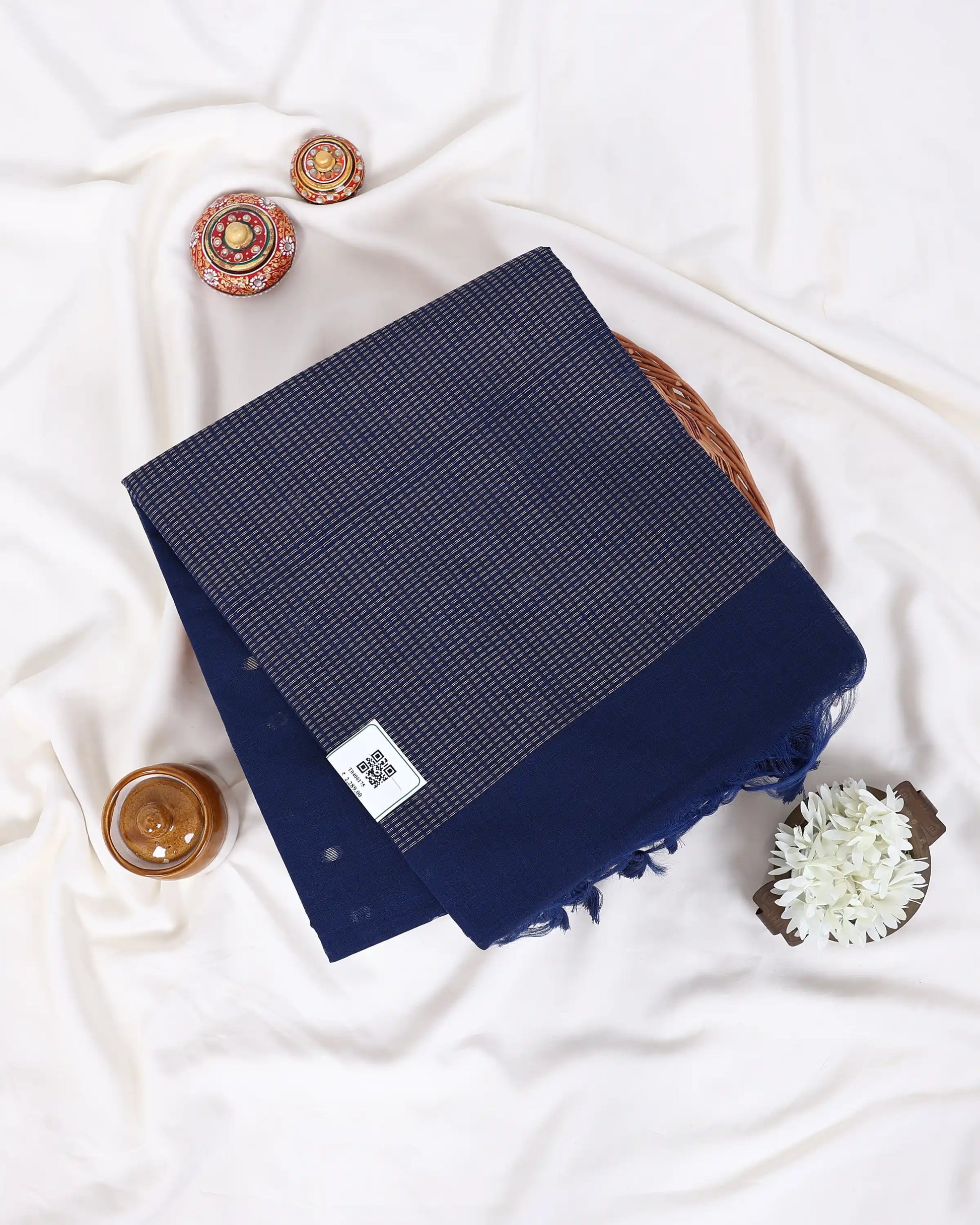 A folded navy blue scarf with a fine woven pattern and fringed edges