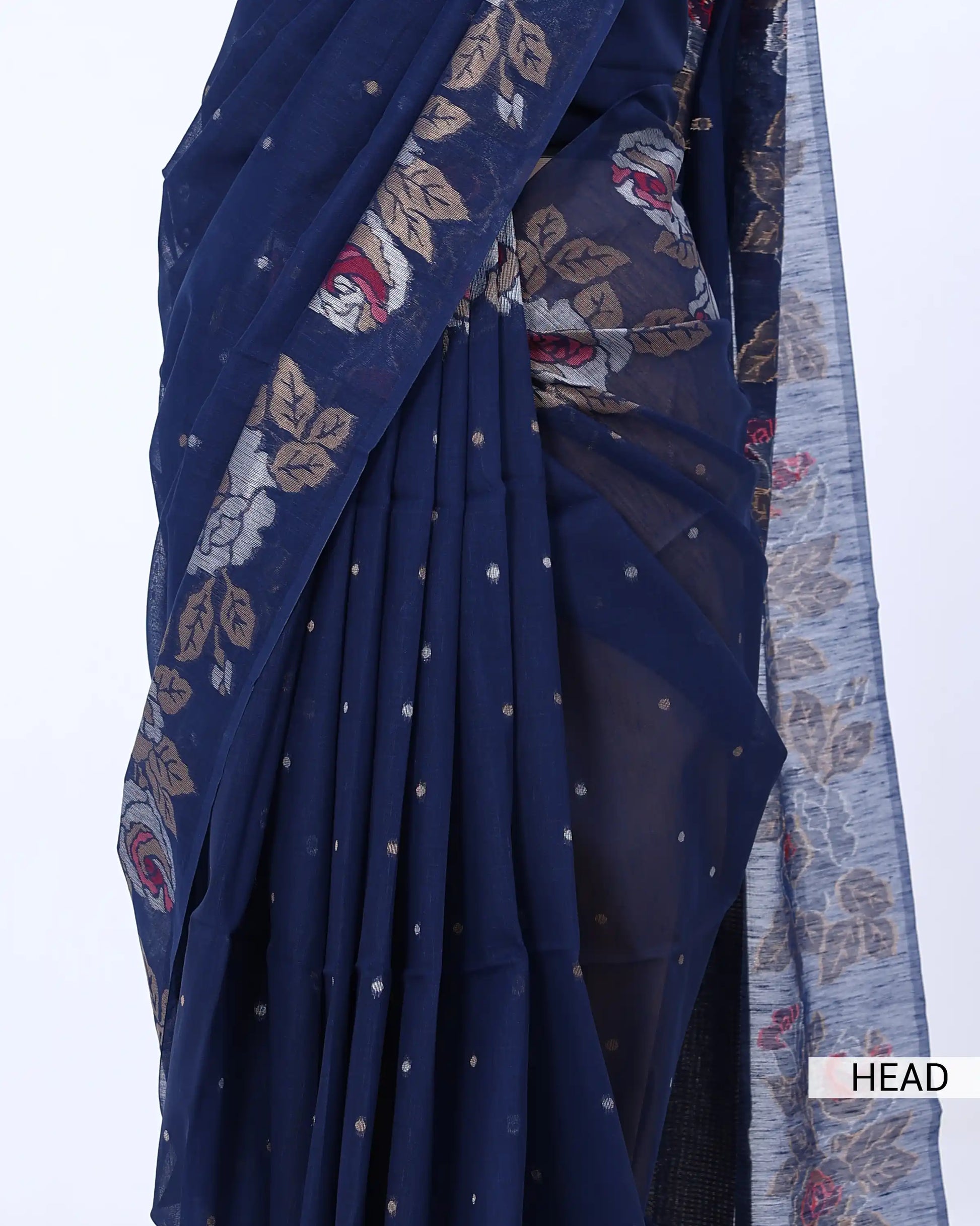 A close-up of a navy blue saree with floral and paisley patterns in beige, red, and white, featuring small metallic dot embellishments
