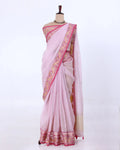 A light pink saree with a wide beige border featuring intricate gold and pink floral patterns