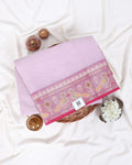 A folded light pink saree with a wide pink border featuring yellow and white floral motifs