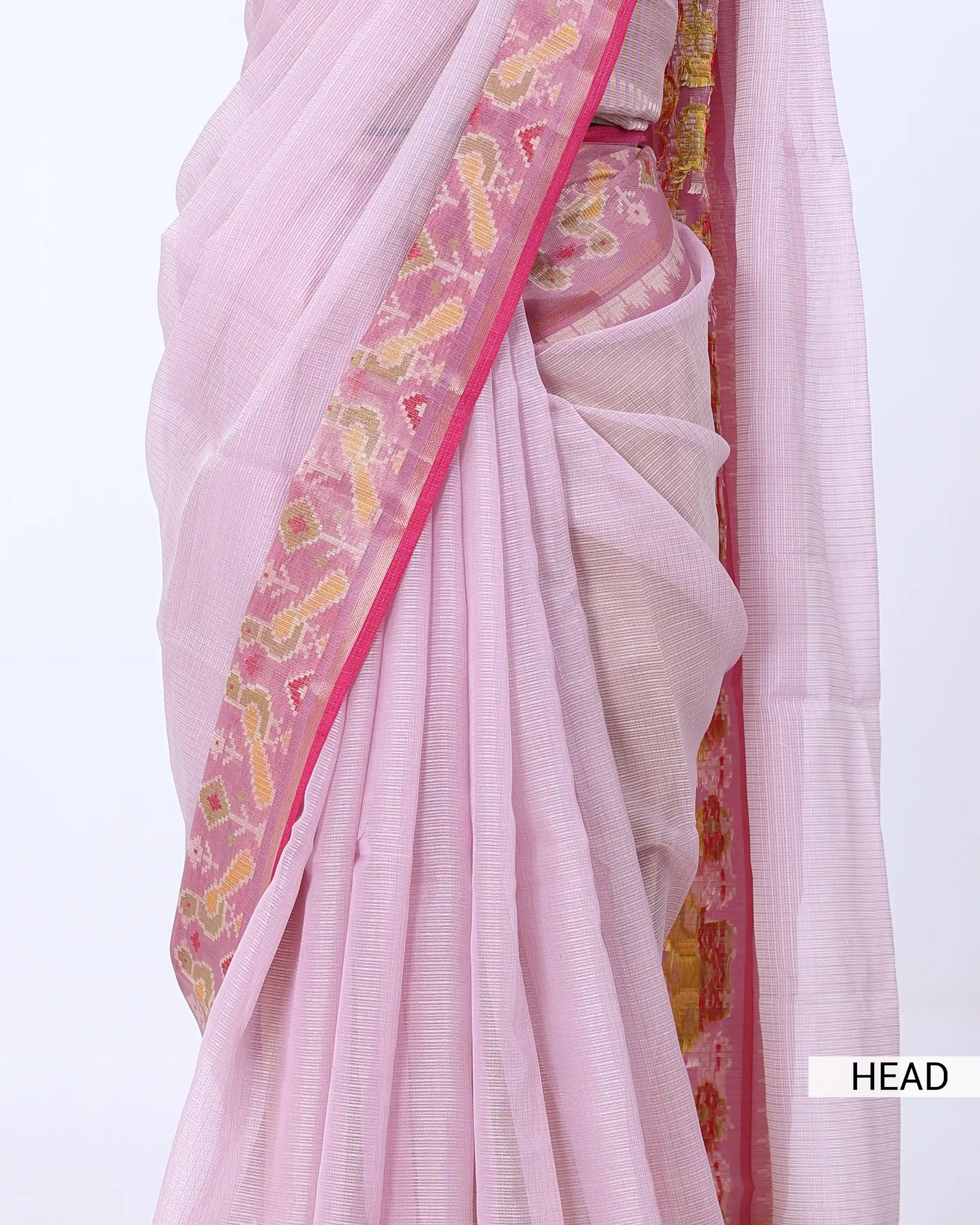 A close-up of a light pink saree with a wide pink border featuring yellow and gold paisley patterns