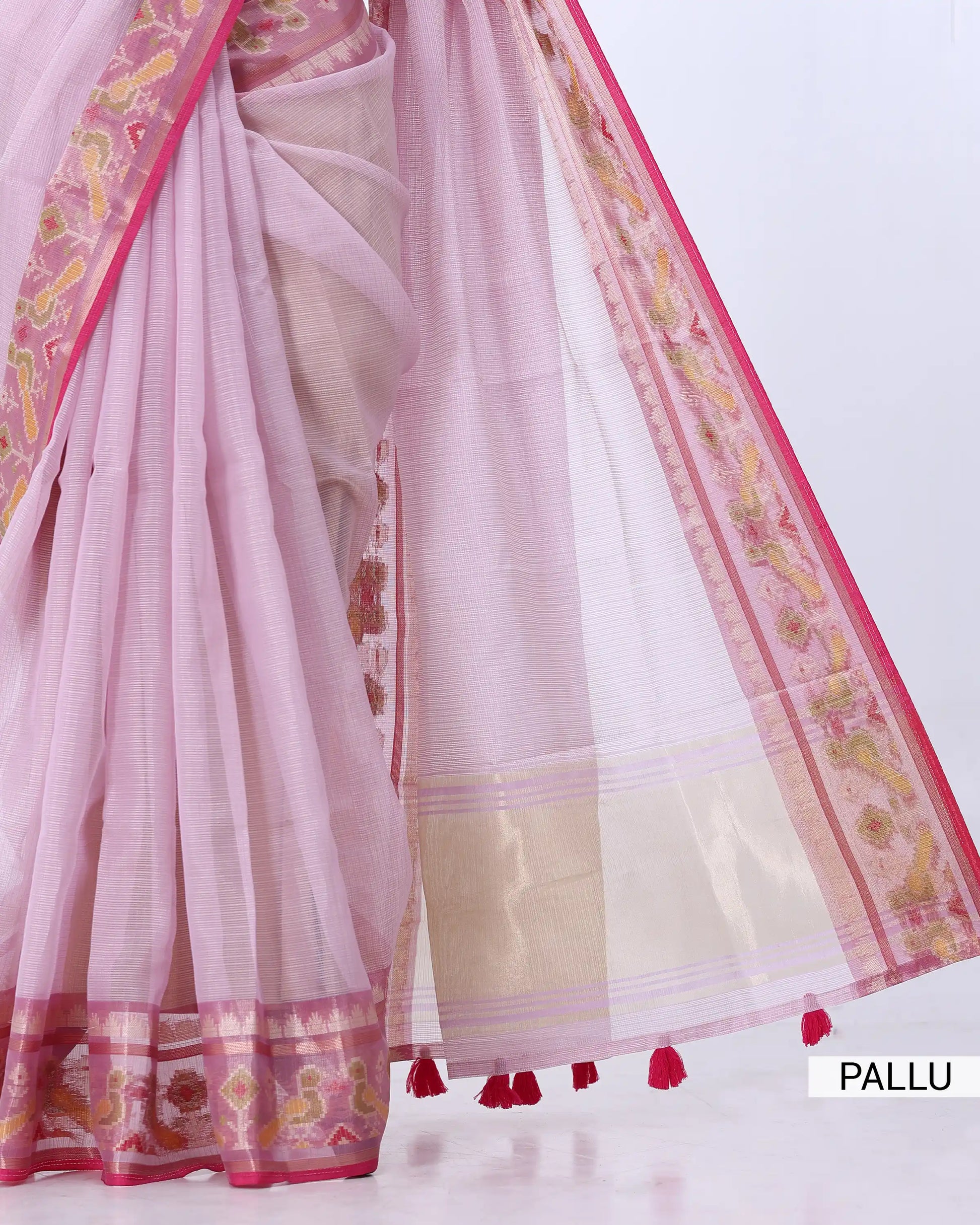 A light pink saree with a beige and pink border, draped to show the pallu
