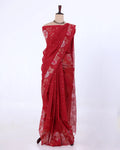 A red saree with gold floral and dot patterns draped on a mannequin against a plain white background.