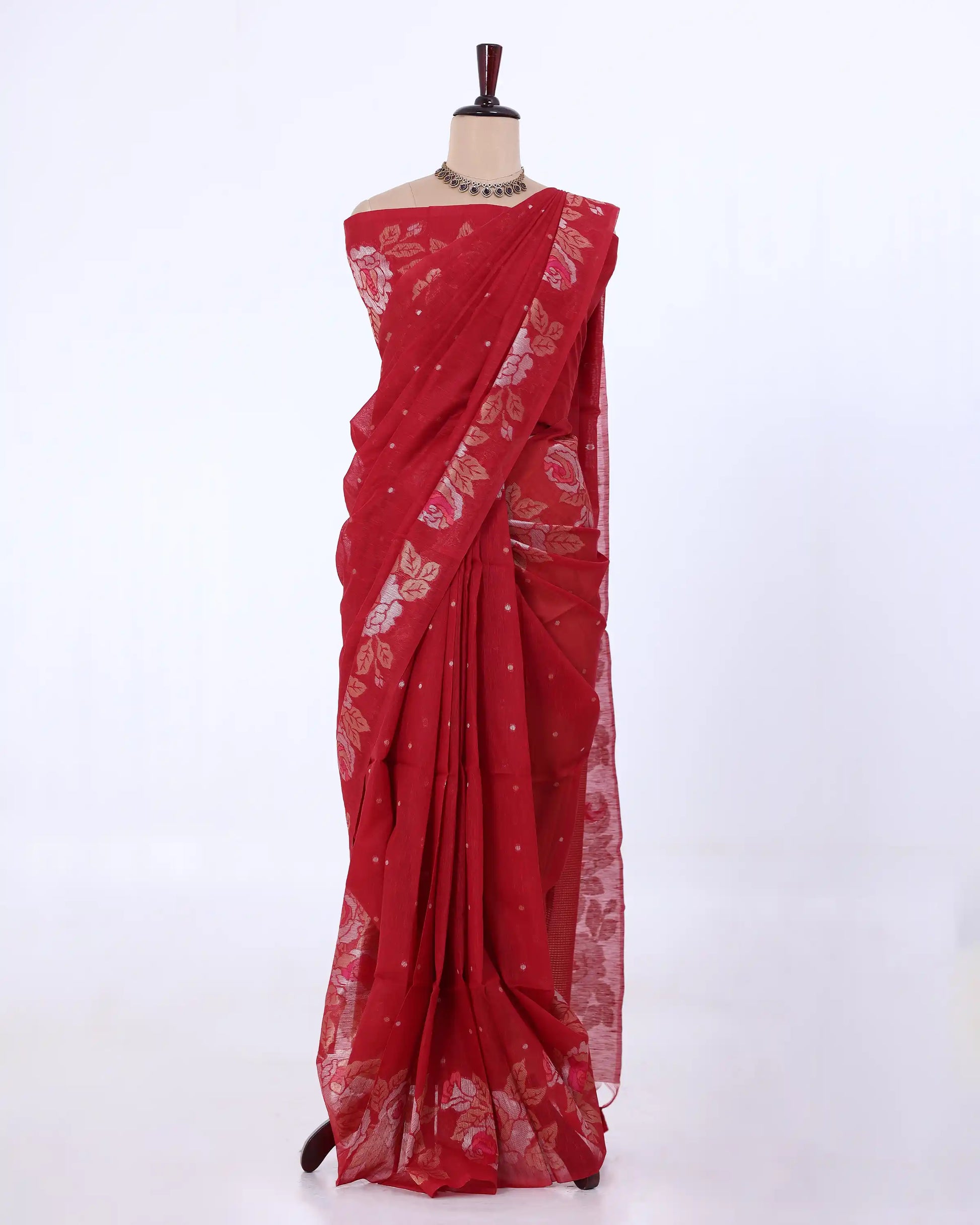 A red saree with gold floral and dot patterns draped on a mannequin against a plain white background.
