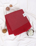 A folded red saree with a subtle woven texture