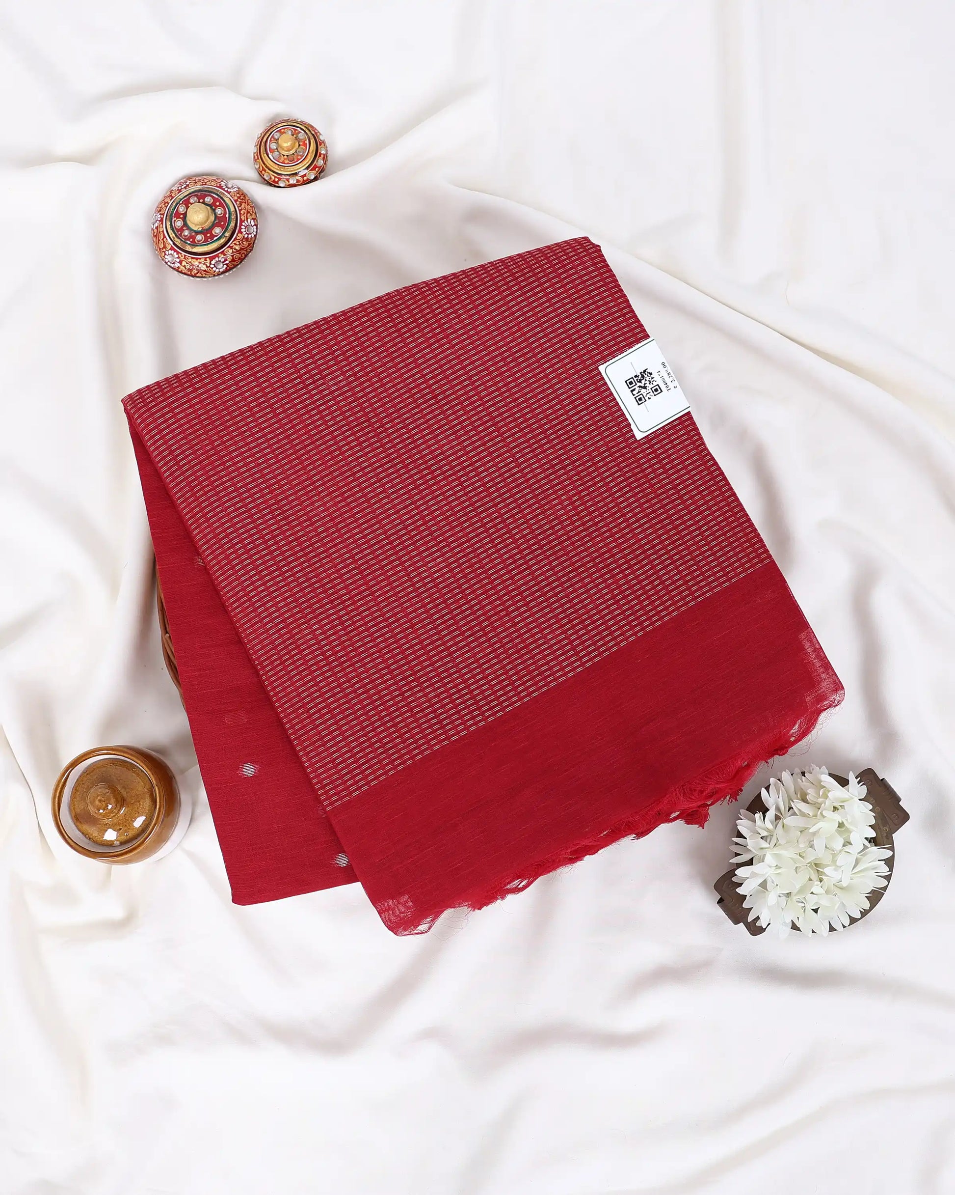 A folded red saree with a subtle woven texture