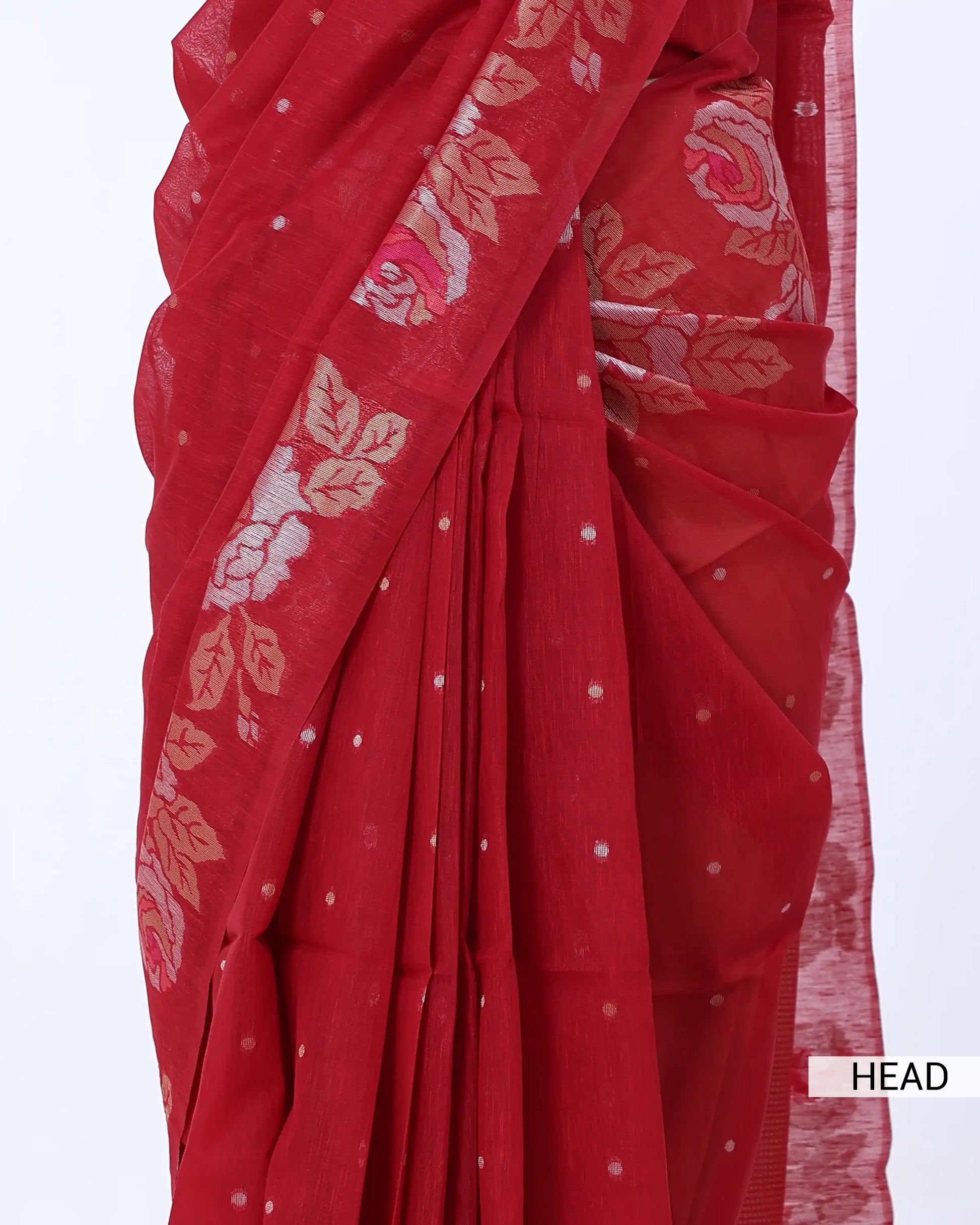 A close-up of a red saree with a border featuring pink and beige floral motifs and small white dots