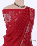 A red cotton saree with a matching printed blouse, displayed on a mannequin torso. The saree features a floral pattern and small metallic dot motifs