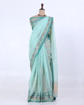A light mint green saree with a floral patterned border and a beige pallu
