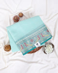 A folded light aqua blue saree with a detailed multicolor border featuring peacock motifs