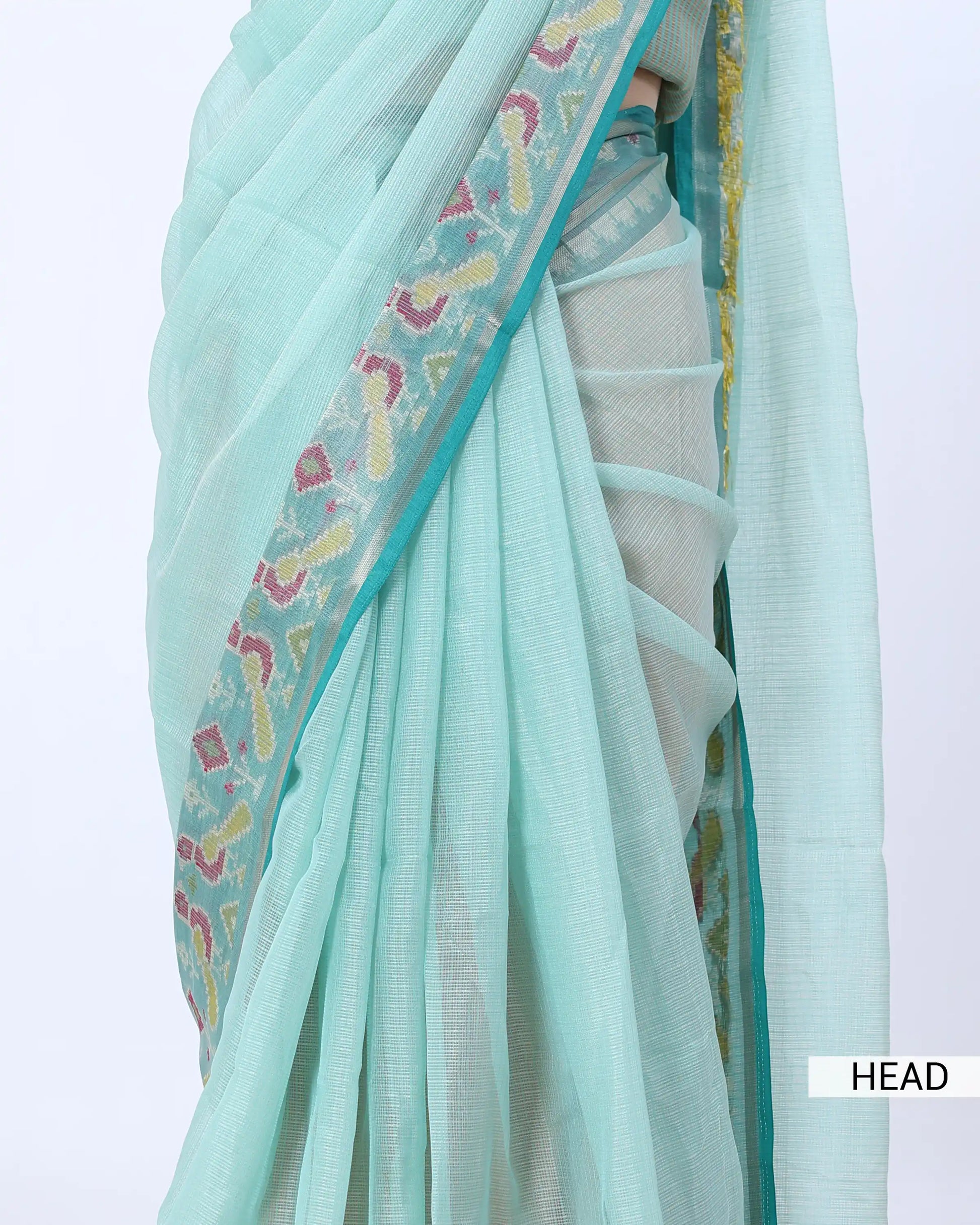 A close-up of a mint green saree showing the fabric texture, pleats, and a decorative border with pastel paisley motifs. 