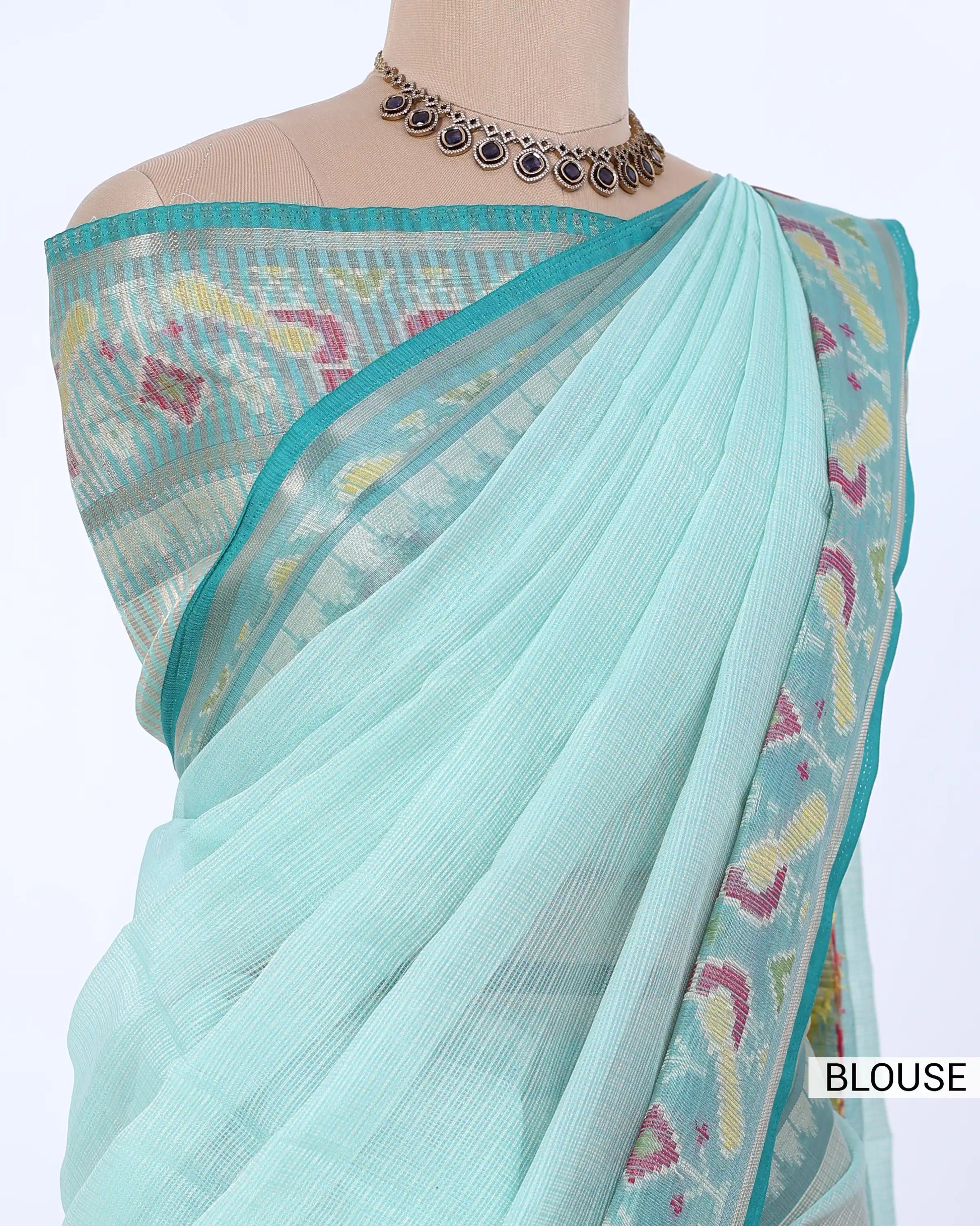 A light aqua blue saree with a matching blouse featuring colorful ikat patterns, 