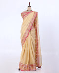 A cream-colored saree with pink and gold borders