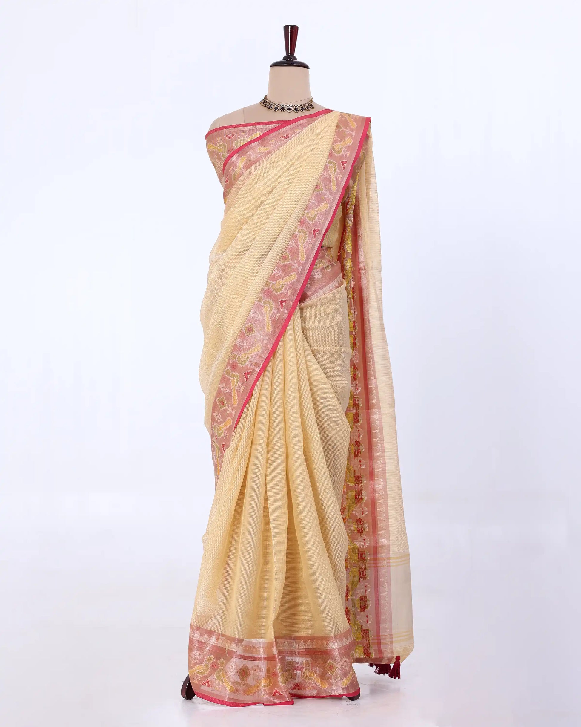 A cream-colored saree with pink and gold borders