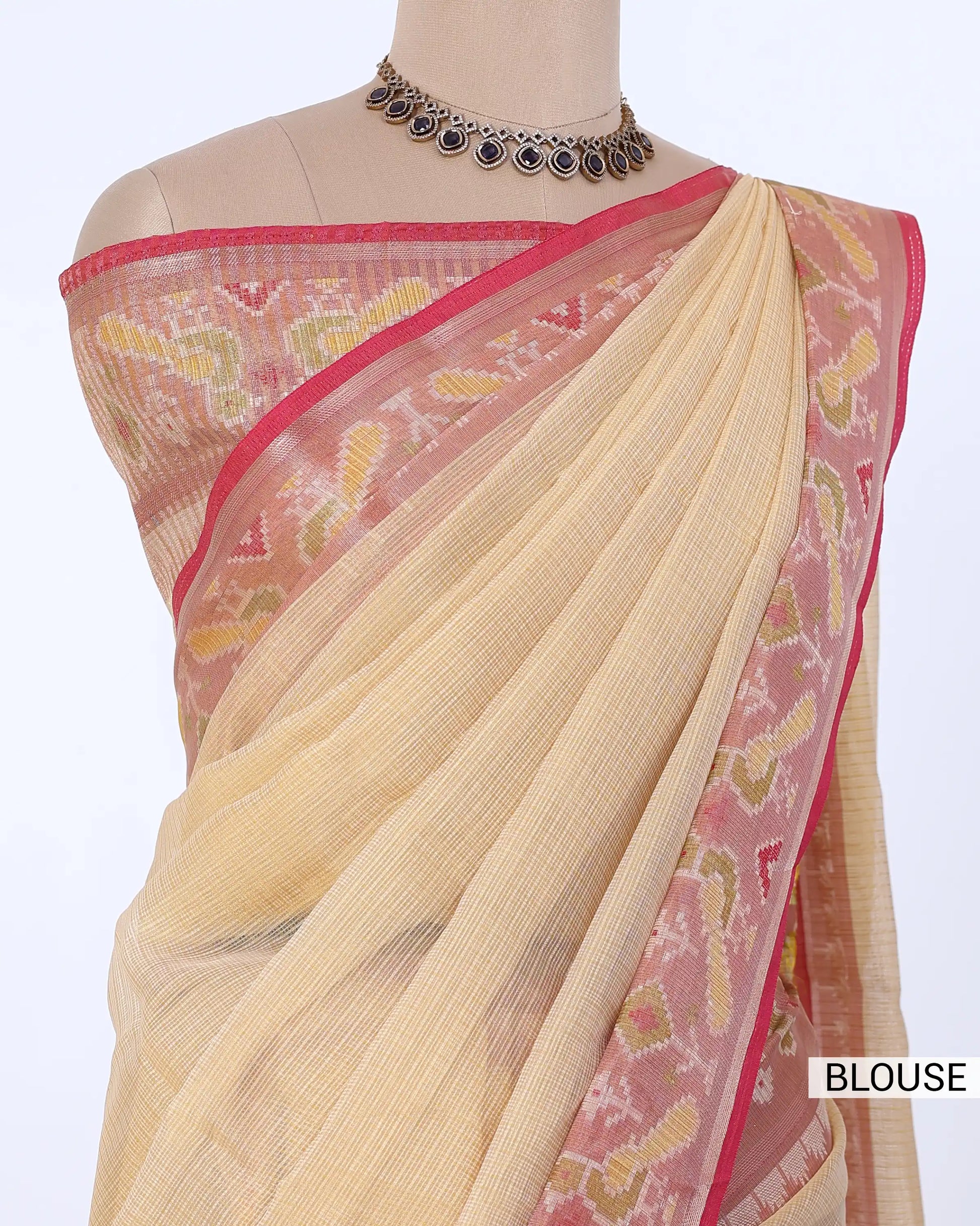 A draped beige and pink saree with yellow and red woven patterns with a matching pink patterned blouse 
