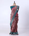 A draped sari has a dusty rose-pink body with a teal-blue border and a matching teal blouse, plus subtle metallic woven detailing.