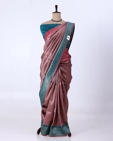 A draped sari has a dusty rose-pink body with a teal-blue border and a matching teal blouse, plus subtle metallic woven detailing.