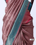 A close-up of a draped sari in dusty rose pink with a wide teal border featuring metallic floral motifs