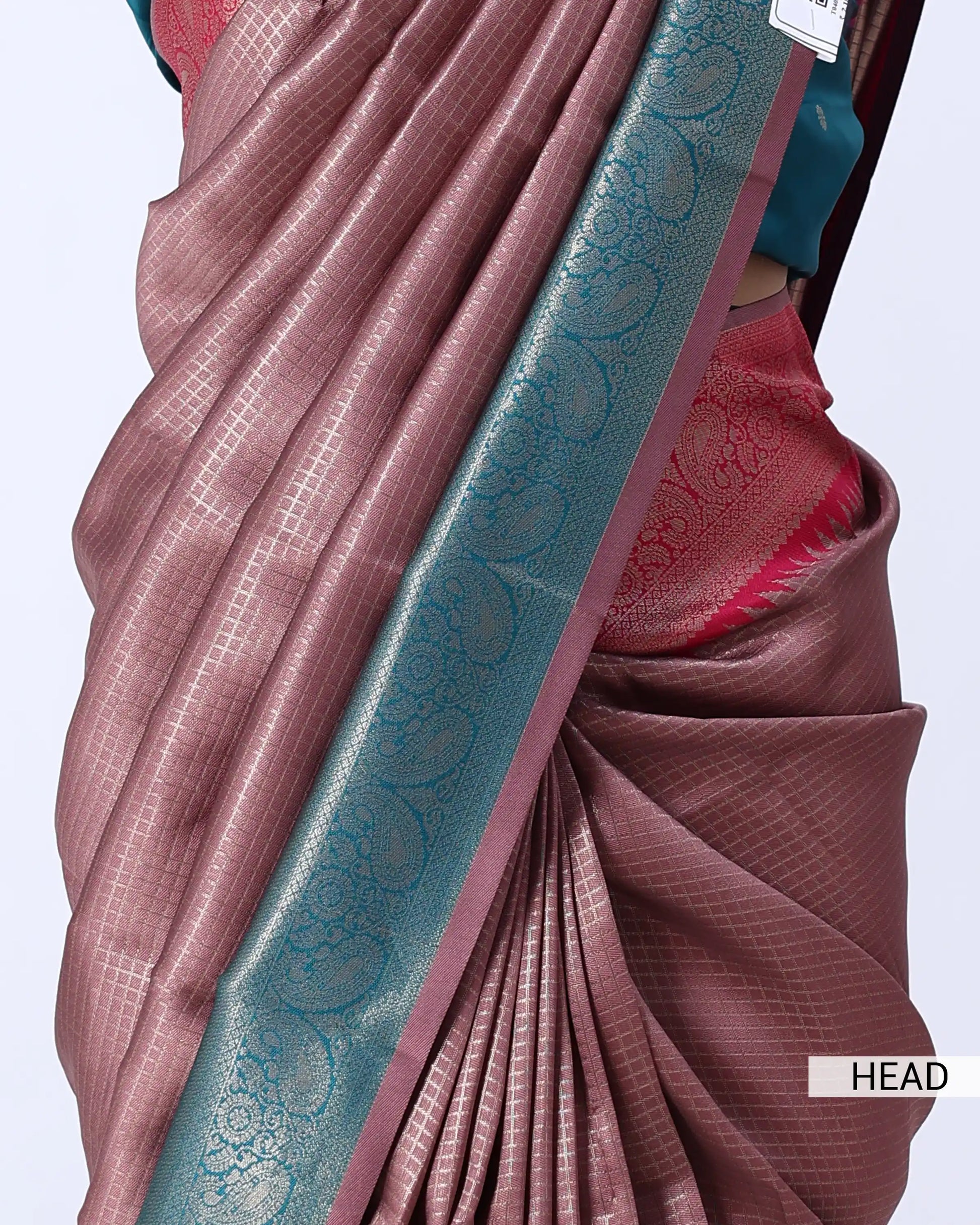 A close-up of a draped sari in dusty rose pink with a wide teal border featuring metallic floral motifs
