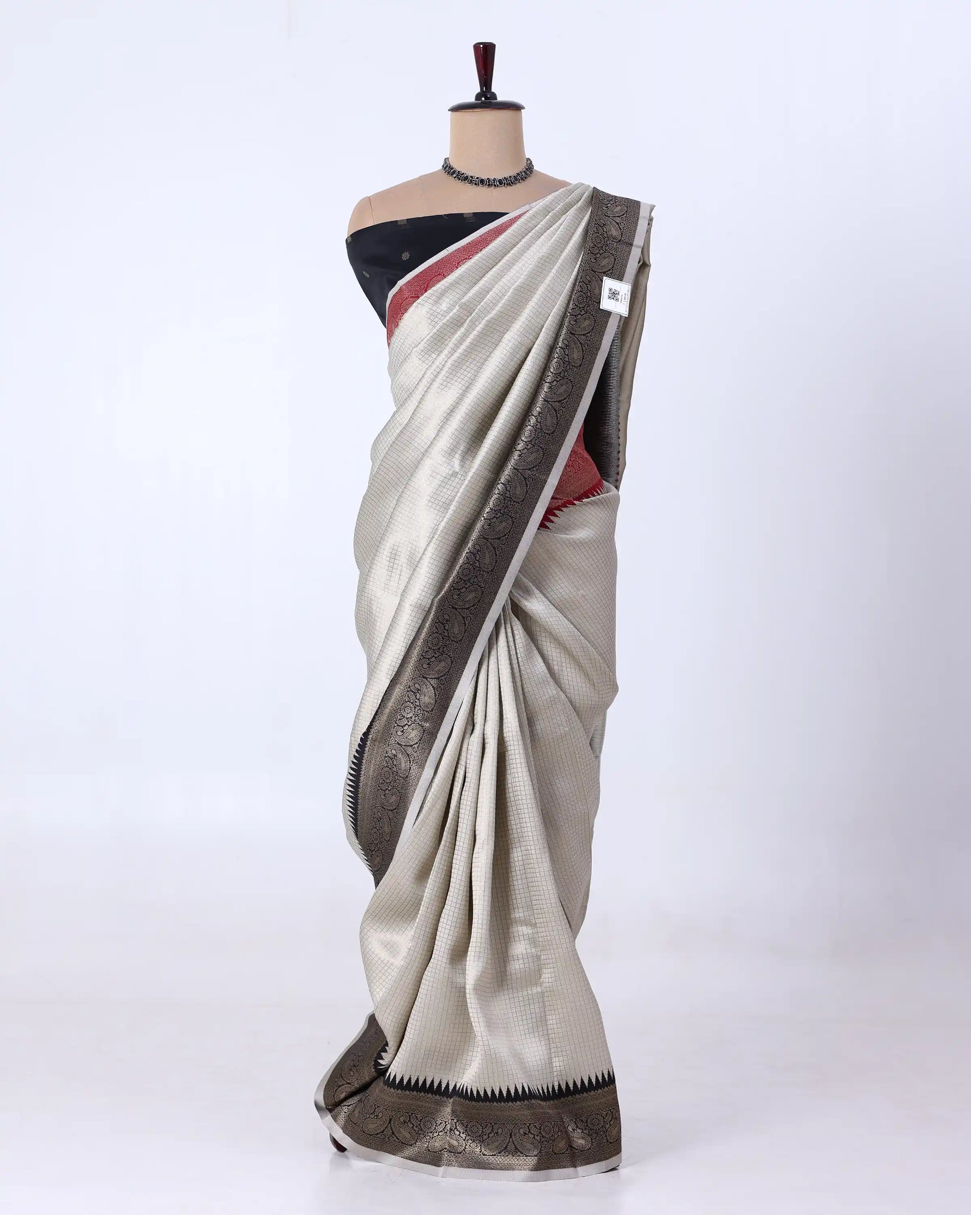 A light beige silk saree with a metallic bronze border and a black blouse