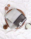 A folded light gray and white checkered saree with a dark gray border and black pointed pattern