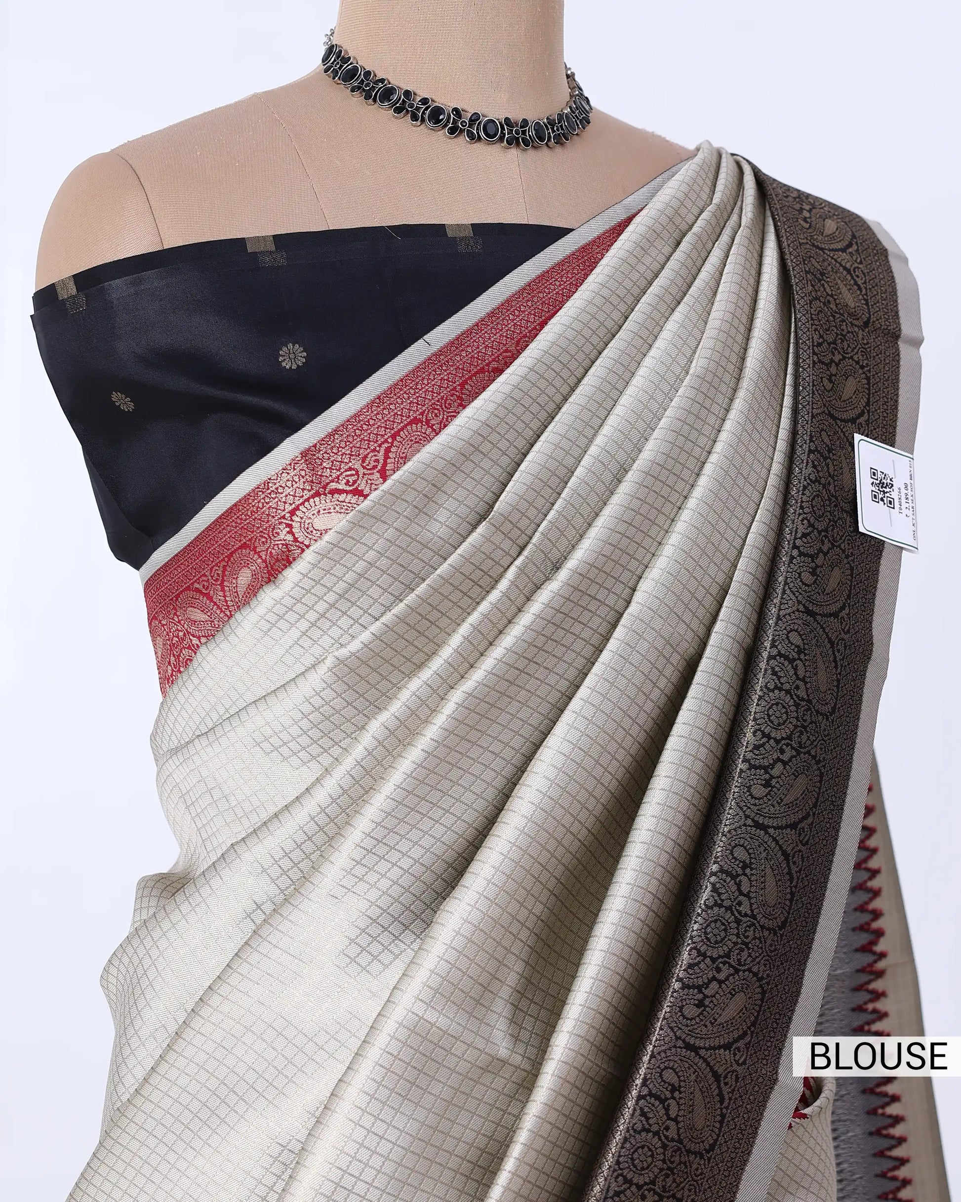 A beige and black checkered saree featuring a dark navy blue blouse with a red border and a wide black paisley border