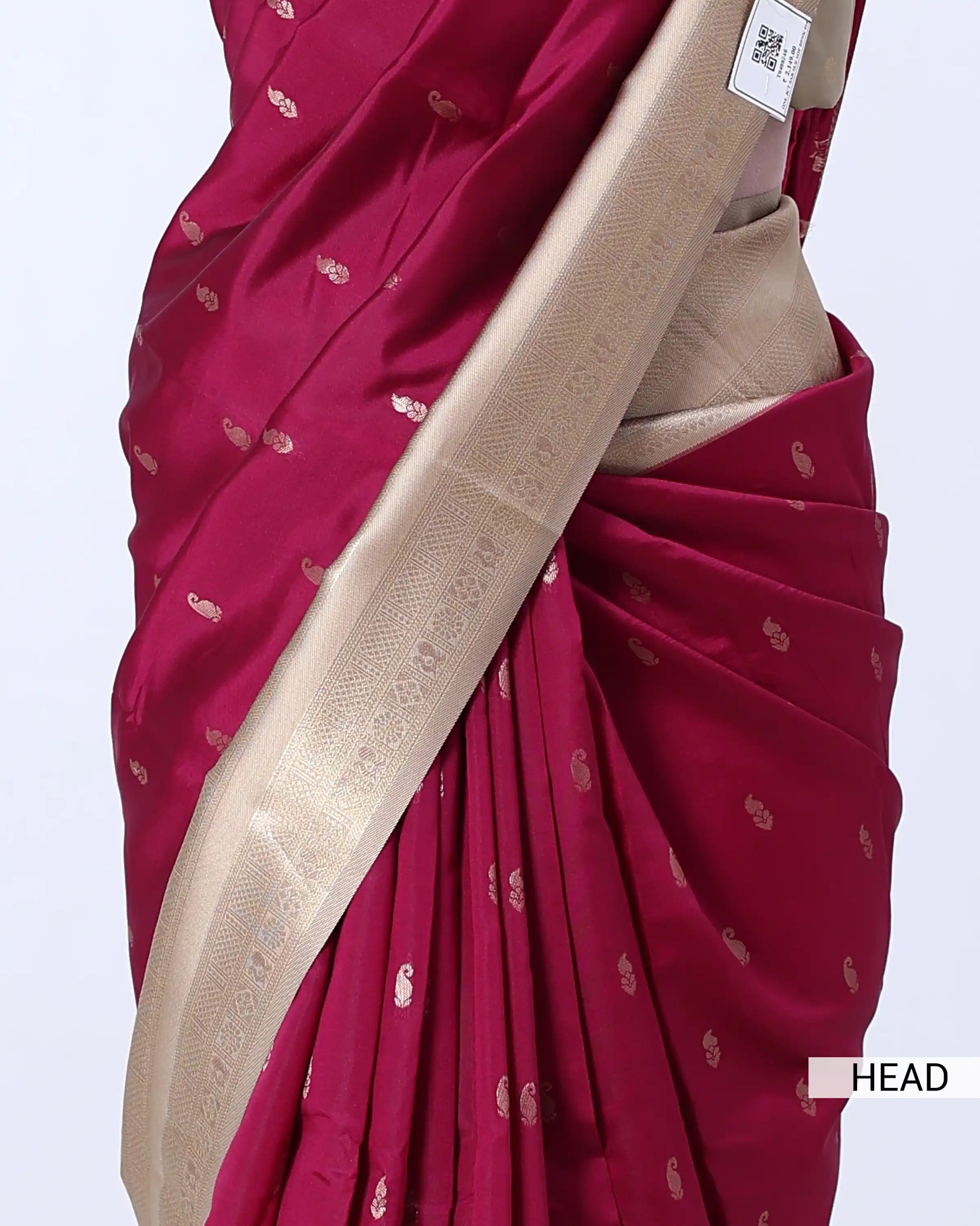 A close-up of a draped saree in deep magenta with small metallic motifs and a wide beige border