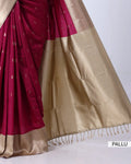 A close-up of a silk saree with a deep magenta body, small gold motifs, and a wide shimmering gold pallu border
