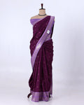 A deep purple silk saree with a lighter purple border and small metallic motifs