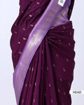 A close-up of a draped purple saree with small metallic gold motifs and a wide lavender border