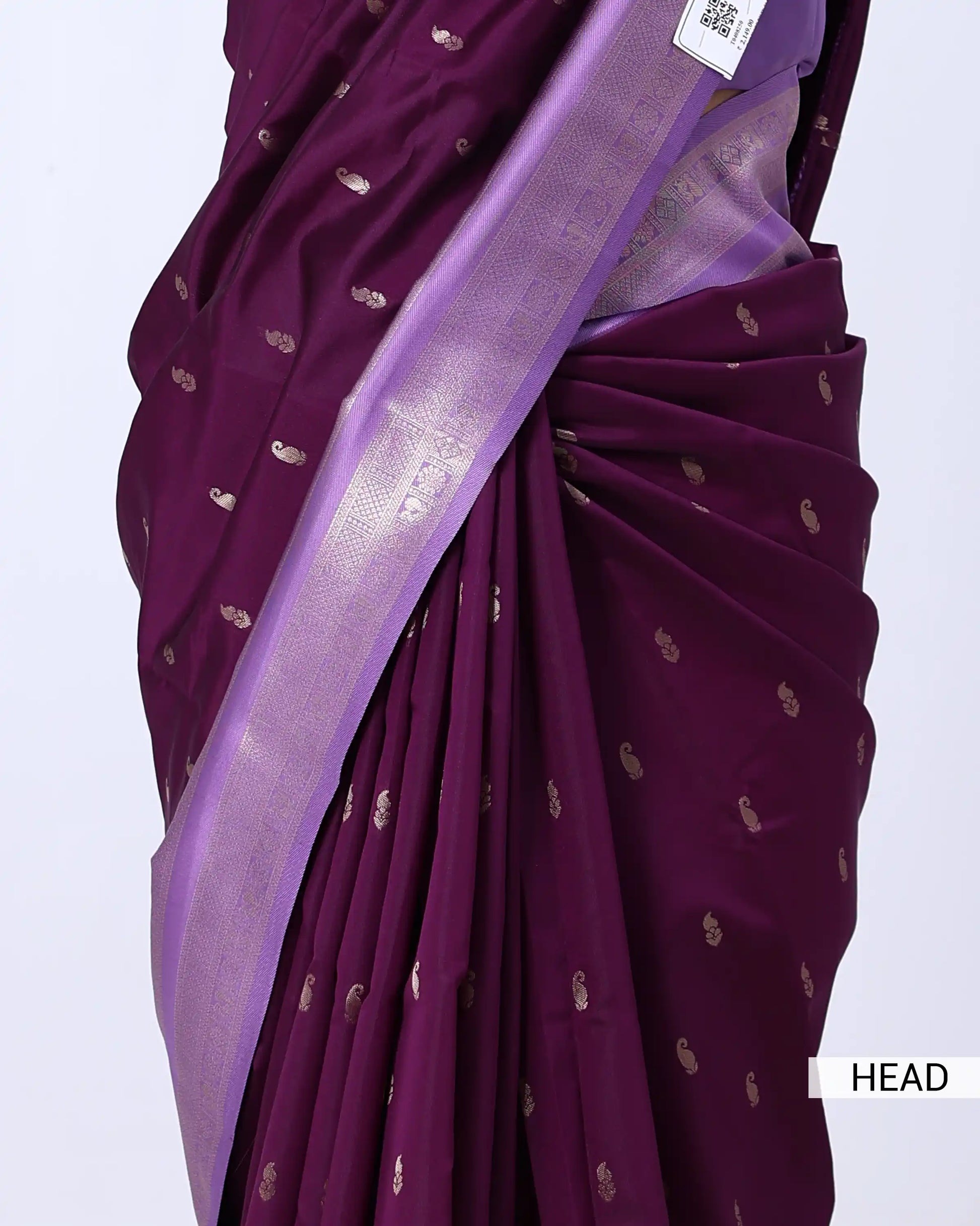 A close-up of a draped purple saree with small metallic gold motifs and a wide lavender border