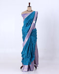 A teal blue and lavender purple saree  features a teal body with small white motifs, a lavender purple border, and a matching lavender purple blouse.