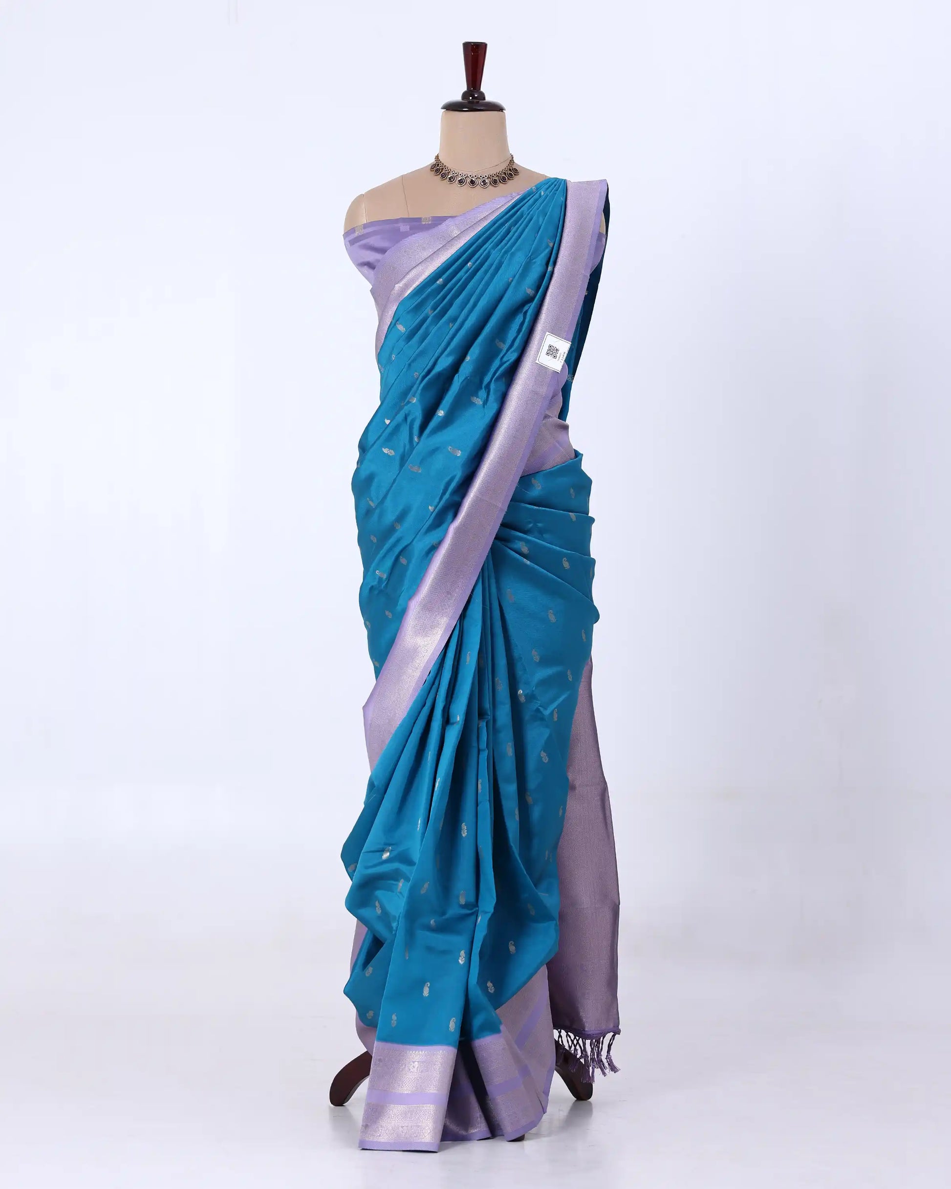 A teal blue and lavender purple saree  features a teal body with small white motifs, a lavender purple border, and a matching lavender purple blouse.