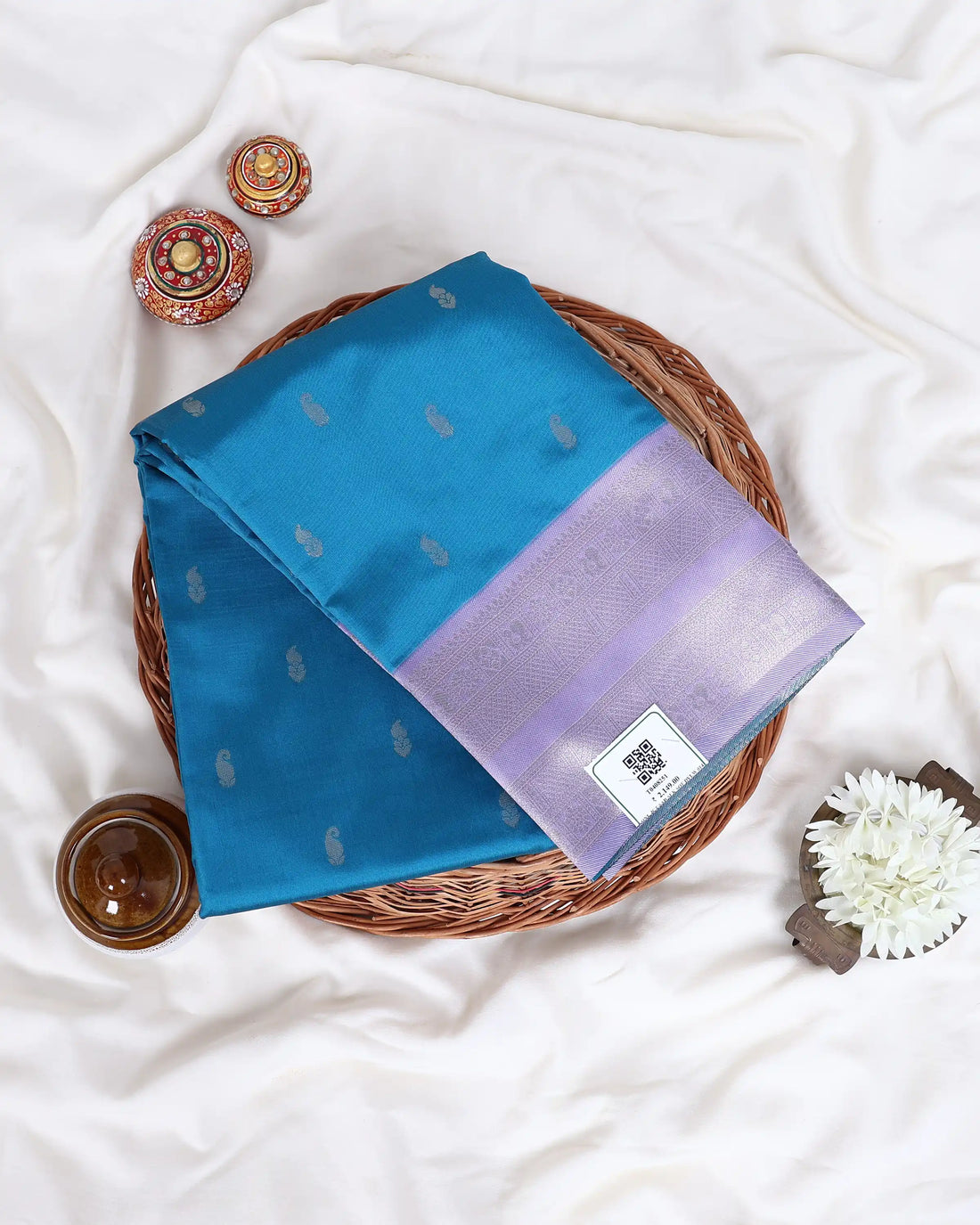 A teal blue and lavender purple saree  features a teal body with small white motifs, a lavender purple border, and a matching lavender purple blouse.