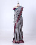 A gray silk saree with a deep purple border and a matching purple blouse 