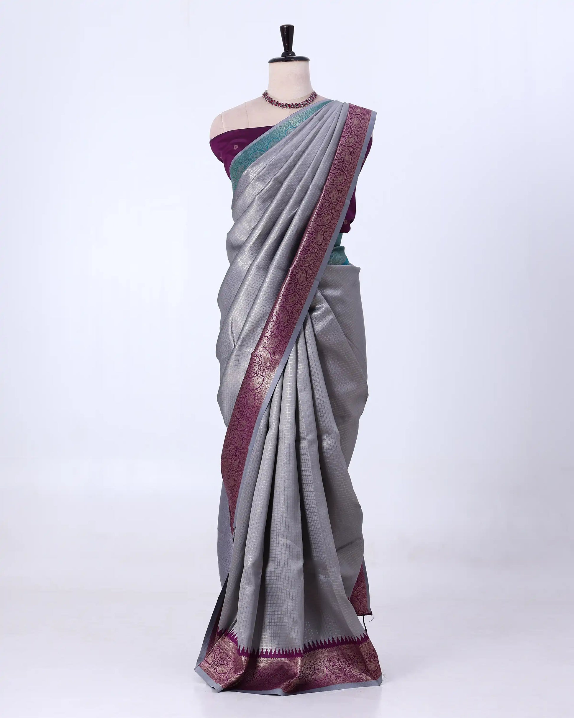 A gray silk saree with a deep purple border and a matching purple blouse 