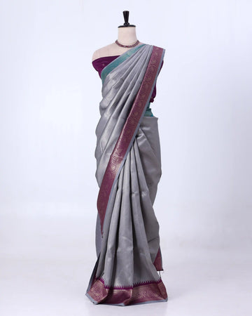 A gray silk saree with a deep purple border and a matching purple blouse 