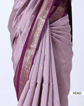 A close-up of a draped lavender saree with metallic gold motifs and a contrasting magenta border with silver zari embroidery