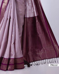A close-up of a traditional Indian saree, showing the pallu end. The fabric is a light lavender-pink color with a rich, dark plum purple border and a metallic gold zari border.