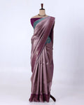 A draped purple saree with a teal-green blouse and a metallic purple border